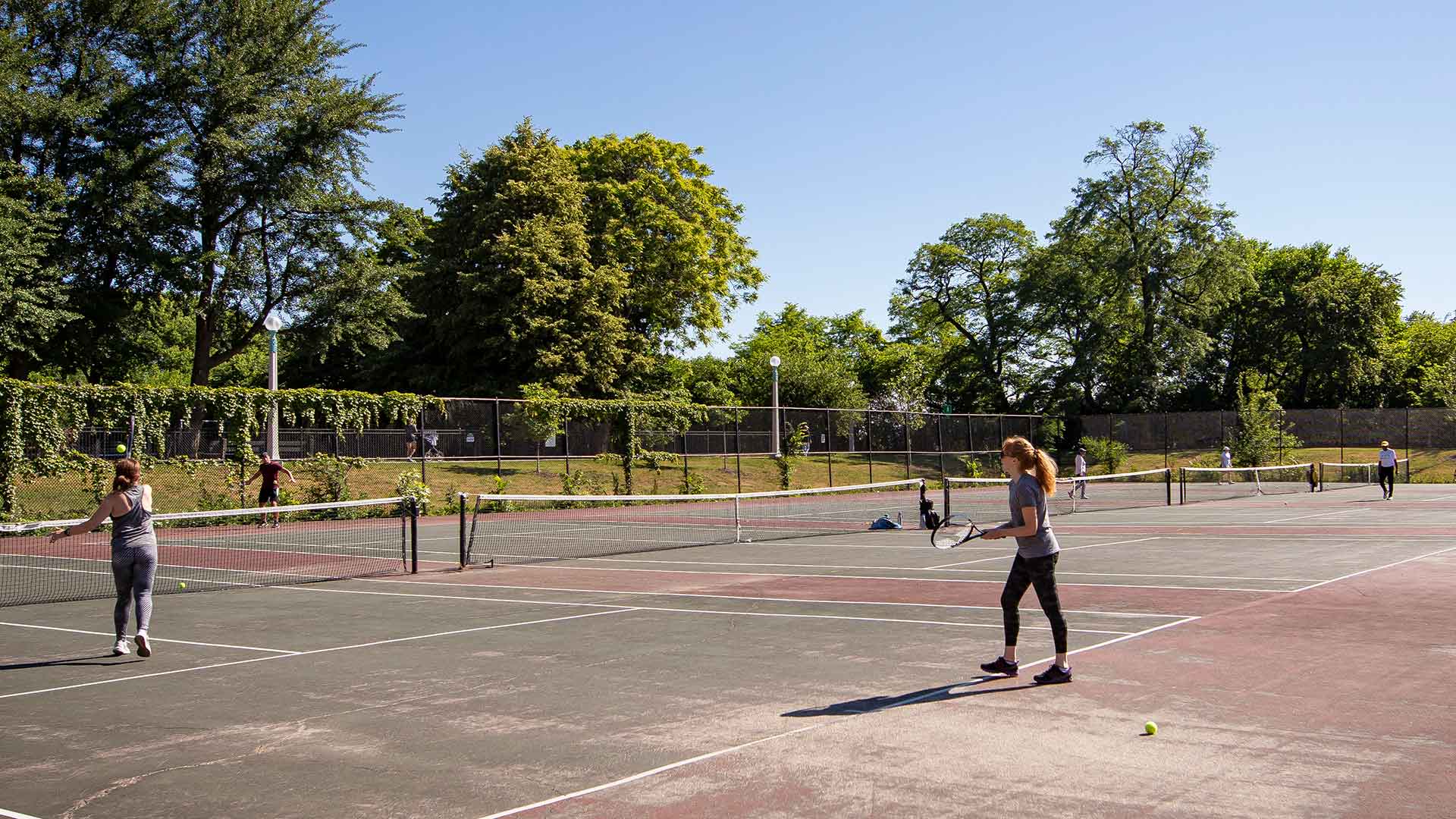 Several people playing tennis on a clear, sunny day.